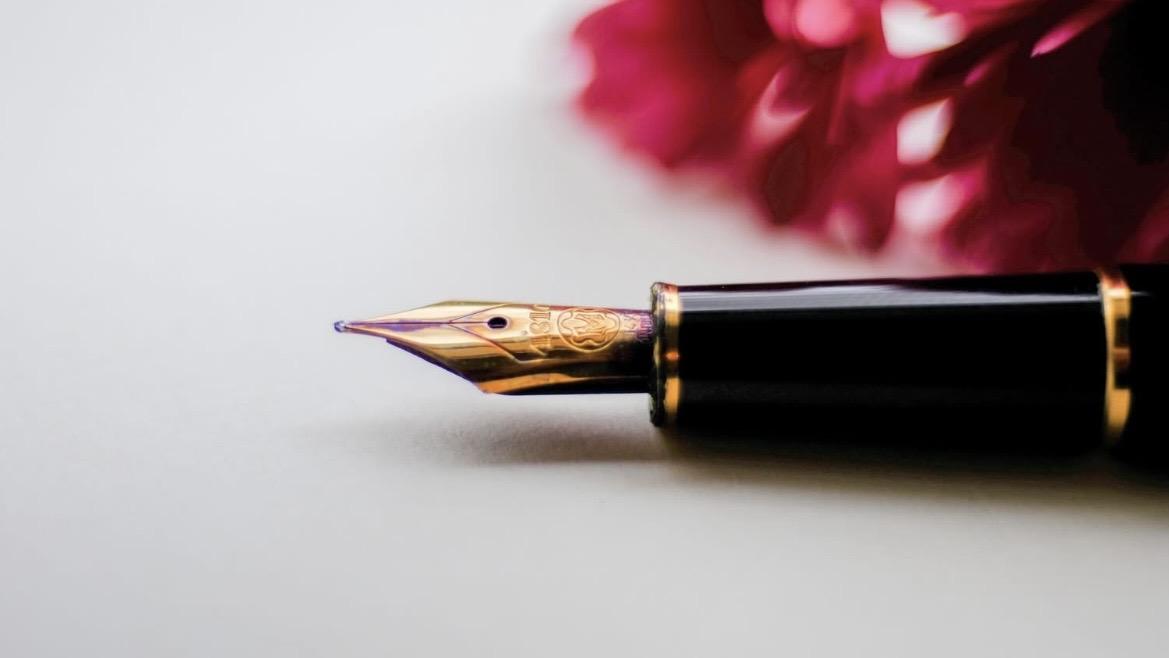 Fountain pen on paper beside flowers