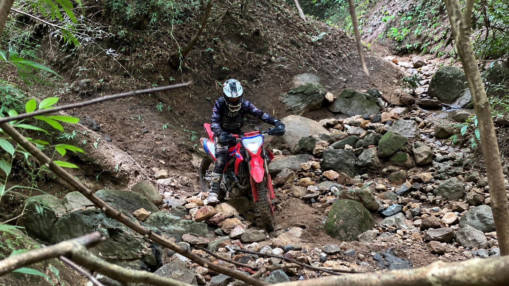 Off-road motorcycle rider navigating rugged jungle terrain